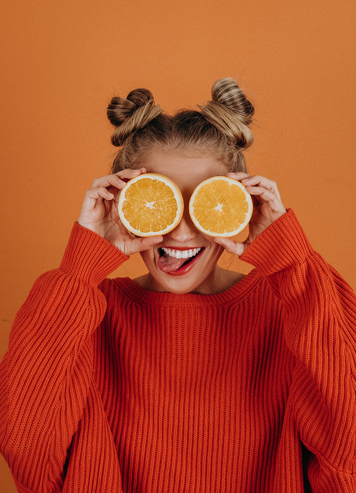 یک دختر که برش پرتقال را روی صورتش گرفته